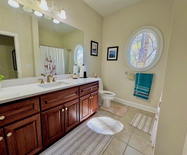 bathroom featuring tile patterned flooring, vanity, toilet, and a healthy amount of sunlight