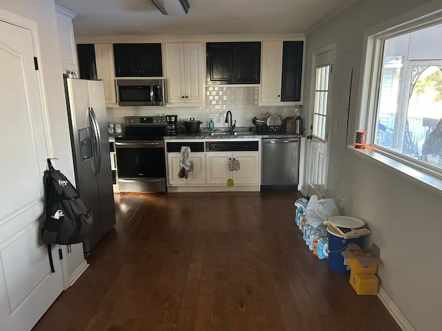 kitchen with appliances with stainless steel finishes, dark hardwood / wood-style floors, tasteful backsplash, white cabinetry, and sink