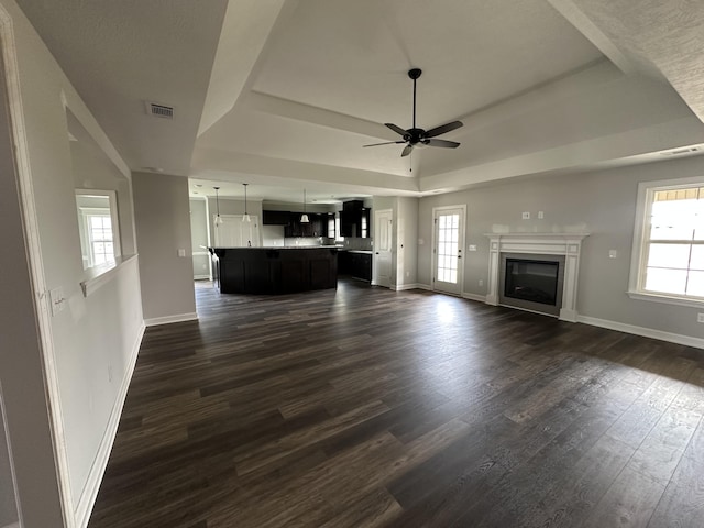 3351 Stockport Dr, Hephzibah, GA 30815 - unfurnished living room featuring a raised ceiling, ceiling fan, baseboards, dark wood finished floors, and a glass covered fireplace