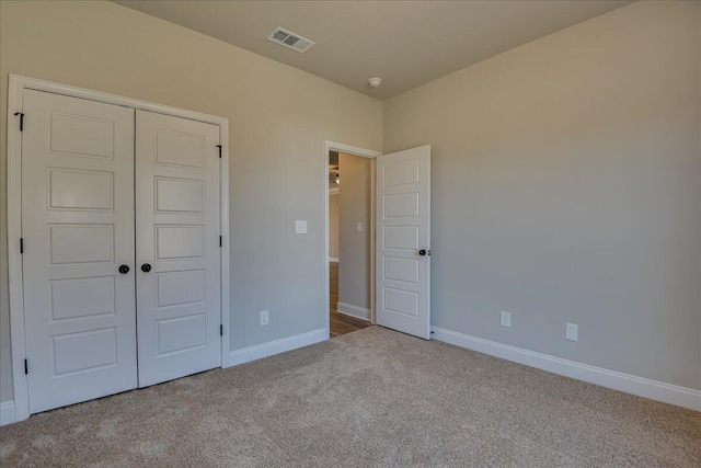 unfurnished bedroom with light carpet and a closet