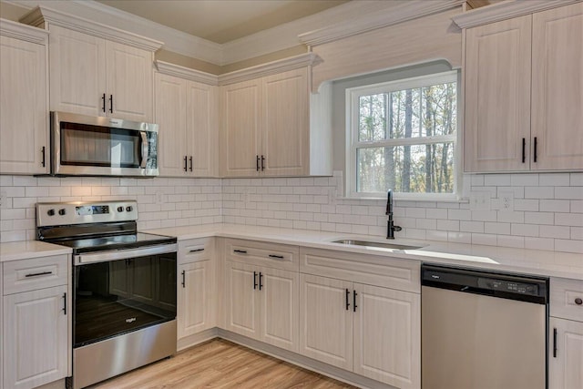 kitchen featuring stainless steel appliances, sink, light hardwood / wood-style flooring, and backsplash