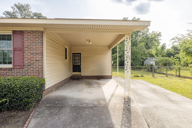 view of patio / terrace with fence, driveway, and a carport