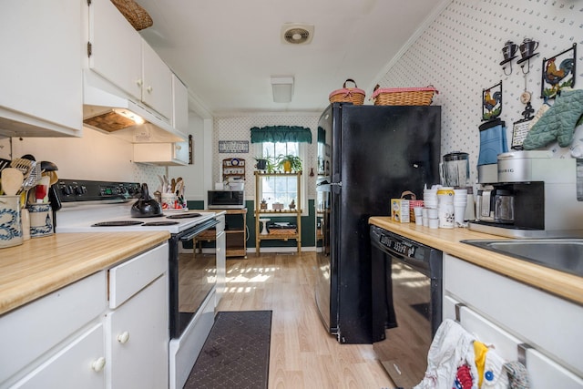 kitchen featuring light countertops, wallpapered walls, black appliances, and light wood-type flooring