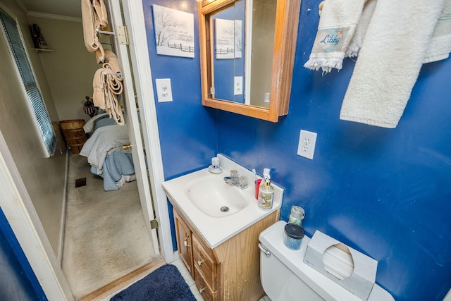 half bath with connected bathroom, toilet, ornamental molding, and vanity