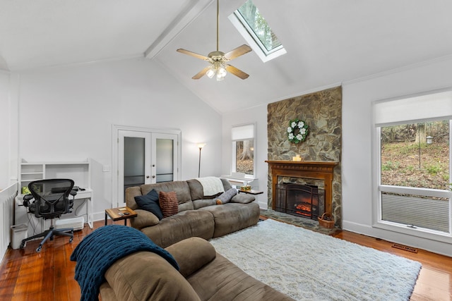 living room with french doors, a stone fireplace, hardwood / wood-style flooring, ceiling fan, and beamed ceiling