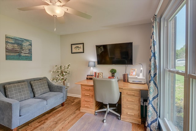 office area with light wood finished floors, a ceiling fan, and baseboards