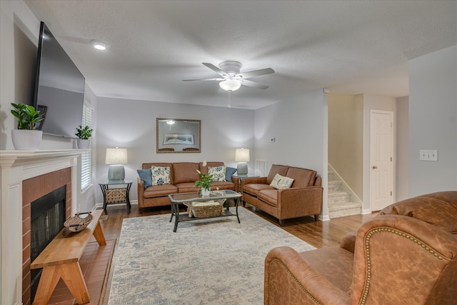 living room featuring a tile fireplace, wood finished floors, ceiling fan, and baseboards