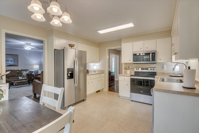 kitchen featuring appliances with stainless steel finishes, light countertops, white cabinets, a sink, and pendant lighting