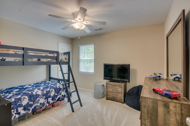 carpeted bedroom featuring a textured ceiling, visible vents, a ceiling fan, and baseboards