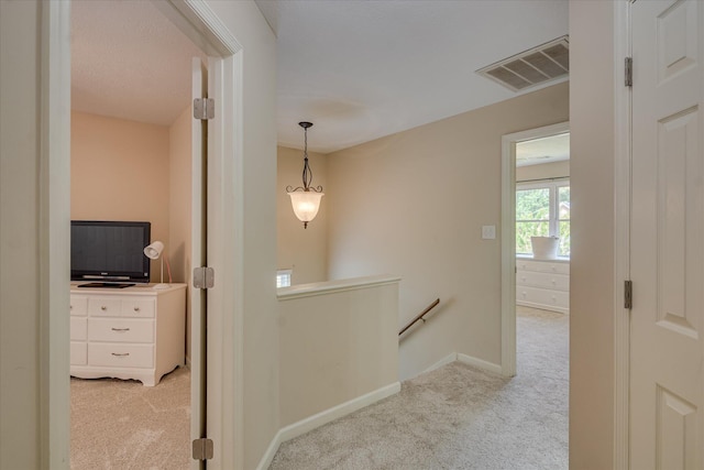 hallway featuring baseboards, visible vents, an upstairs landing, and carpet flooring