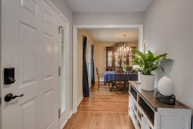 hallway featuring light wood-type flooring and a notable chandelier