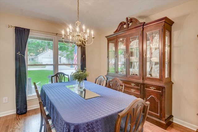 dining room featuring a chandelier, baseboards, and wood finished floors