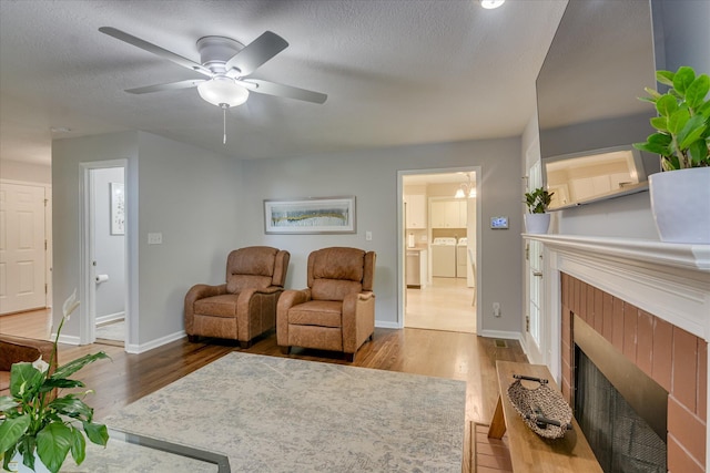 living area featuring a tile fireplace, wood finished floors, separate washer and dryer, and baseboards