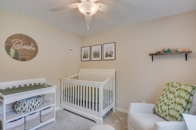 carpeted bedroom with baseboards, a nursery area, and a ceiling fan