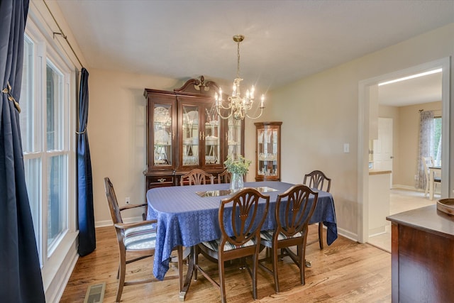 dining space featuring an inviting chandelier, visible vents, baseboards, and light wood-style floors