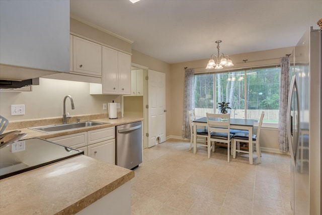 kitchen featuring white cabinets, a sink, appliances with stainless steel finishes, baseboards, and an inviting chandelier