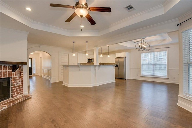 818 Fenwick Ct, Grovetown, GA 30813 - unfurnished living room featuring a raised ceiling, arched walkways, dark wood finished floors, a fireplace, and a decorative wall