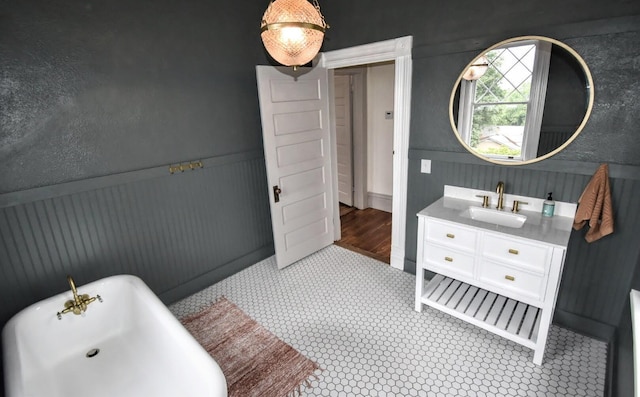 bathroom with vanity, a freestanding tub, and a wainscoted wall