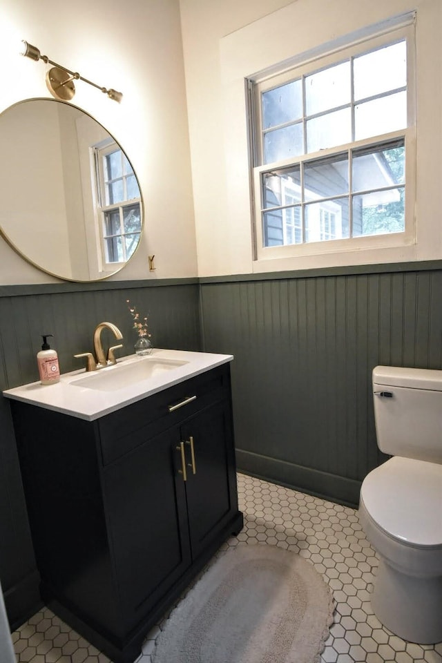 bathroom featuring tile patterned flooring, a wainscoted wall, toilet, and vanity