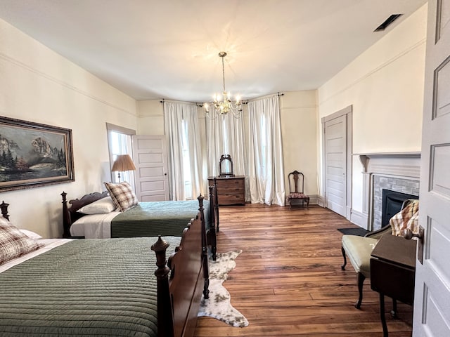 bedroom with a chandelier, visible vents, a fireplace, and wood finished floors