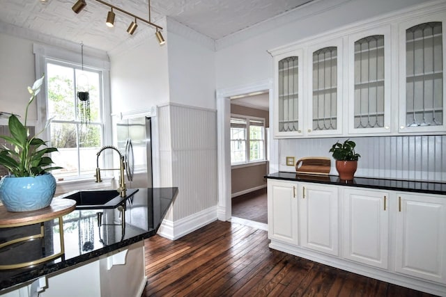 kitchen featuring a sink, dark wood-style floors, white cabinetry, stainless steel fridge, and glass insert cabinets