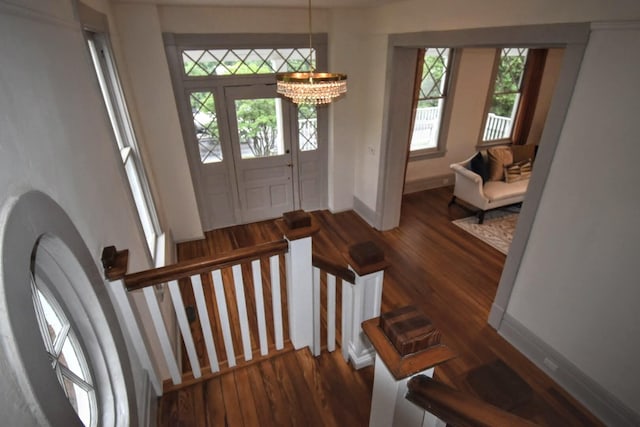 entrance foyer with a chandelier, dark wood-type flooring, and baseboards