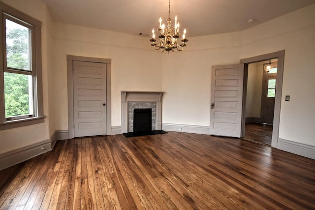 unfurnished living room featuring baseboards, a fireplace with flush hearth, an inviting chandelier, and hardwood / wood-style flooring