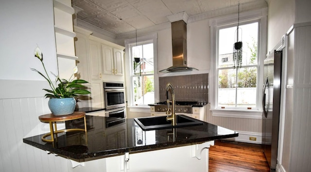 kitchen with a wealth of natural light, dark wood-style floors, wall chimney exhaust hood, and freestanding refrigerator