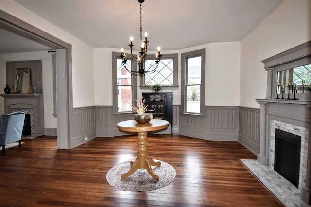 dining room featuring a chandelier, a fireplace with flush hearth, wainscoting, and hardwood / wood-style floors