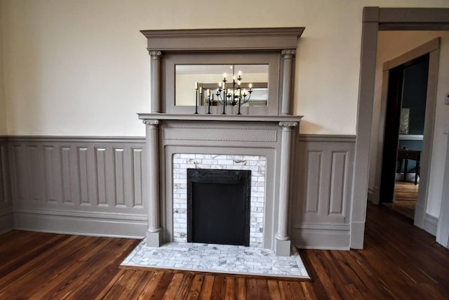 interior details featuring a notable chandelier, wood finished floors, and wainscoting