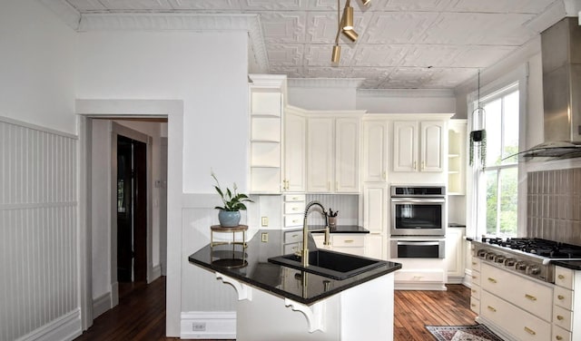 kitchen featuring open shelves, appliances with stainless steel finishes, a peninsula, an ornate ceiling, and a sink