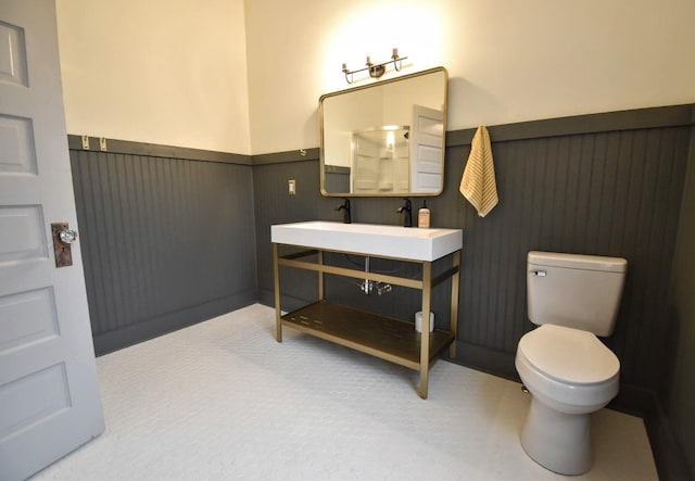 bathroom with a wainscoted wall, toilet, and vanity