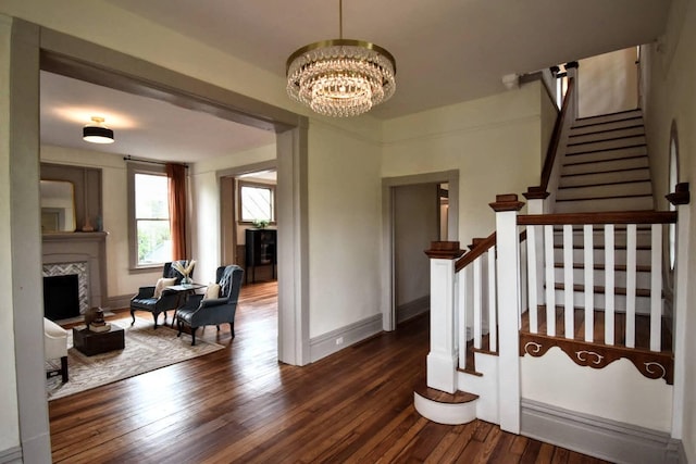 staircase with a chandelier, baseboards, wood finished floors, and a tile fireplace