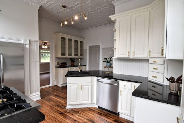 kitchen featuring a sink, dark countertops, stainless steel appliances, a peninsula, and white cabinets