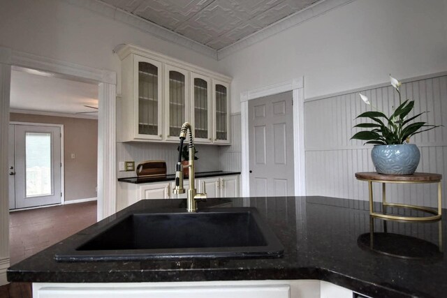 kitchen with dark countertops, ornamental molding, an ornate ceiling, and a sink