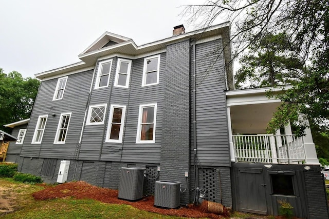 view of side of home with central air condition unit and a chimney