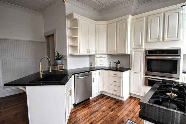 kitchen featuring a peninsula, dark wood-style flooring, an ornate ceiling, a sink, and stainless steel appliances