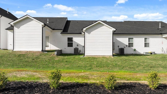 back of property with central AC unit and a lawn