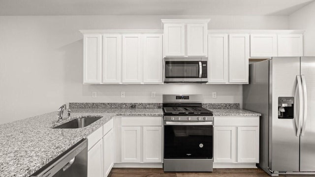 kitchen featuring light stone countertops, sink, appliances with stainless steel finishes, white cabinets, and dark hardwood / wood-style floors