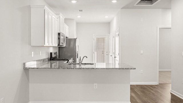 kitchen featuring kitchen peninsula, sink, light stone counters, appliances with stainless steel finishes, and white cabinets