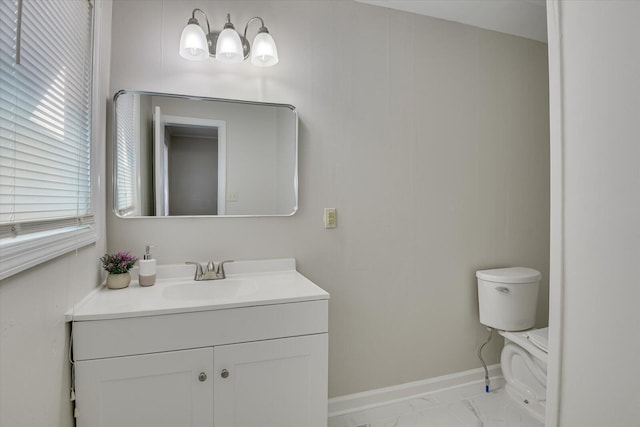 bathroom featuring toilet, marble finish floor, vanity, and baseboards