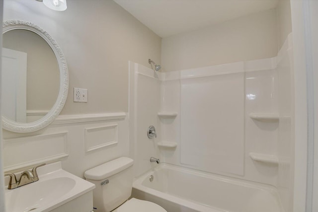 bathroom featuring shower / washtub combination, wainscoting, vanity, and toilet