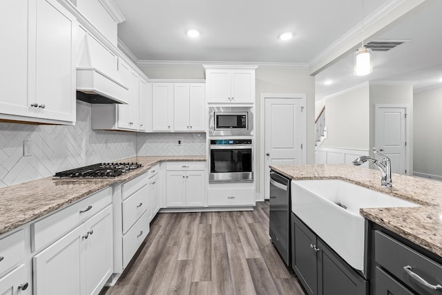 kitchen with a sink, decorative light fixtures, ornamental molding, white cabinets, and appliances with stainless steel finishes
