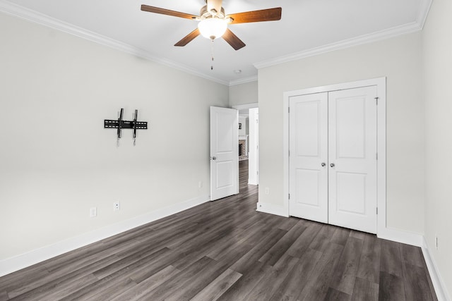 unfurnished bedroom with a closet, ornamental molding, dark wood-style flooring, baseboards, and a ceiling fan