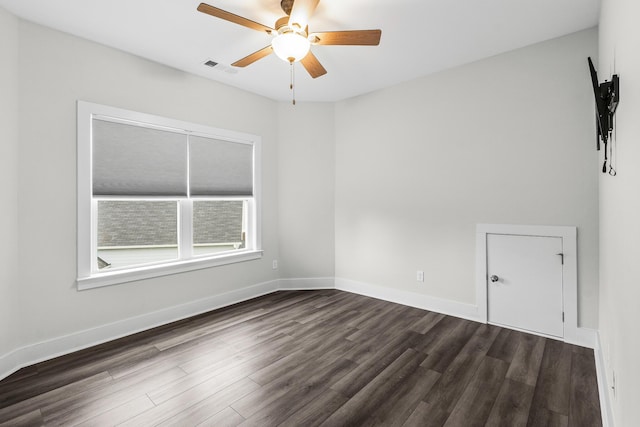 empty room with a ceiling fan, visible vents, baseboards, and dark wood-type flooring