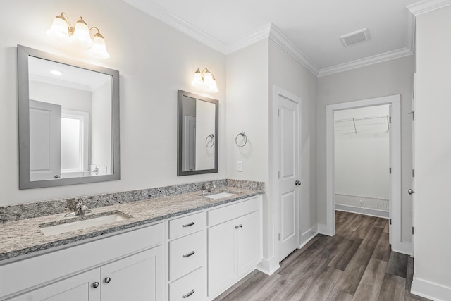 bathroom featuring ornamental molding, a sink, wood finished floors, and visible vents