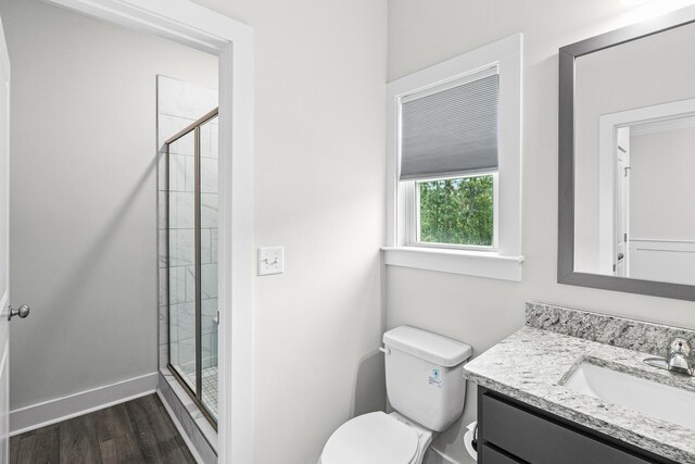 full bathroom with a stall shower, baseboards, toilet, wood finished floors, and vanity