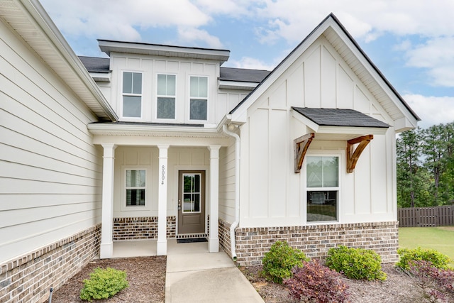 entrance to property with fence, board and batten siding, and brick siding
