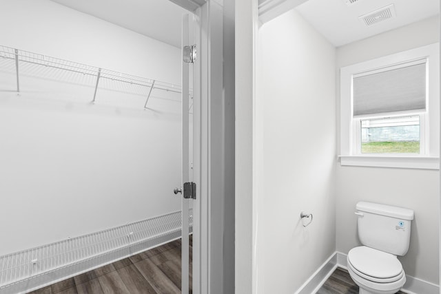 bathroom featuring wood finished floors, visible vents, toilet, and baseboards