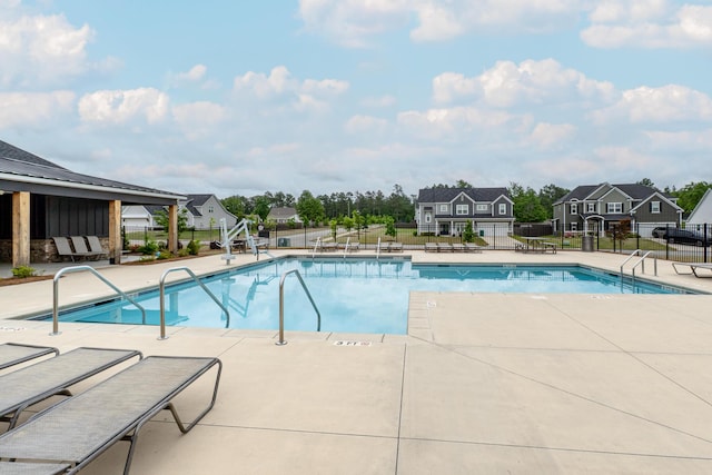pool with a residential view, a patio area, and fence